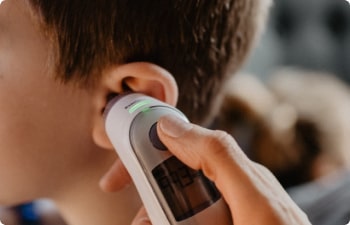 Someone using an electronic themometer to check a child's temperature